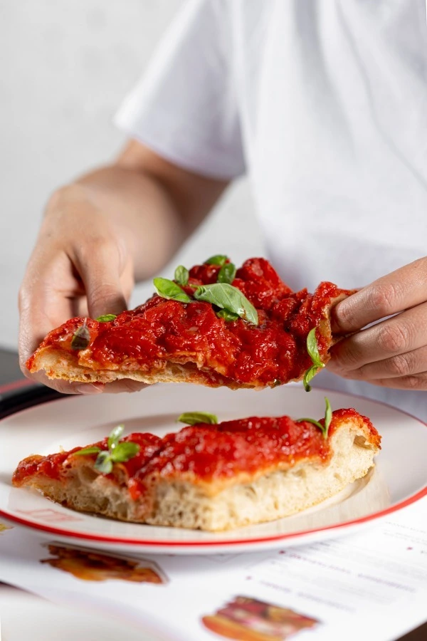 Focaccia on a platter with tomato sauce and basil