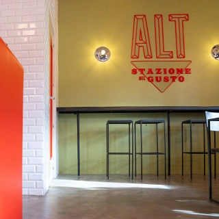 ALT Stazione del Gusto logo on wall of an ALT store, table bar and stools